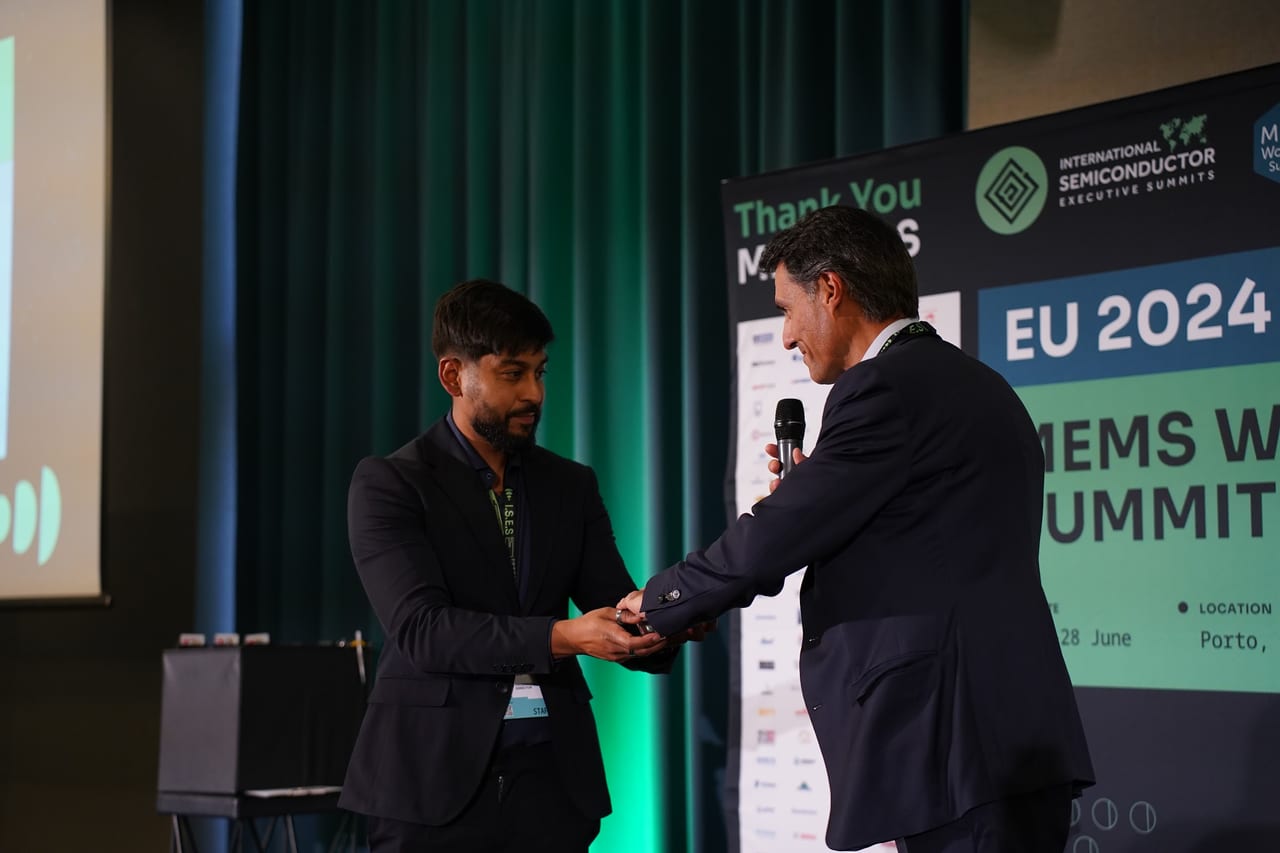 An award handshake on stage at the MEMS World Summit, Porto