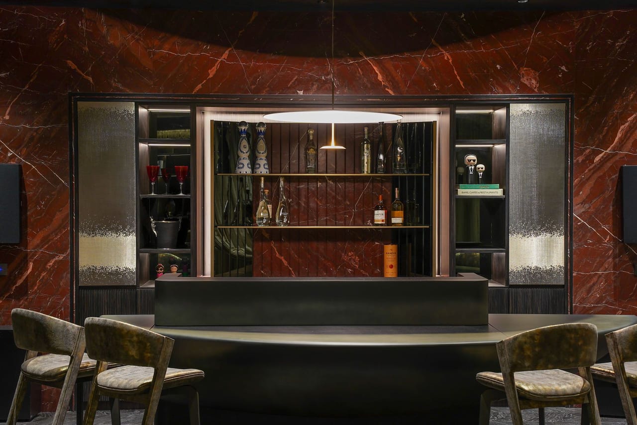 A bar with a red marble wall, timber cabinetry and high stools