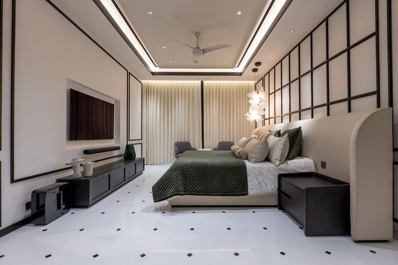 A bedroom with a dark green bed, panelled walls and a white marble floor