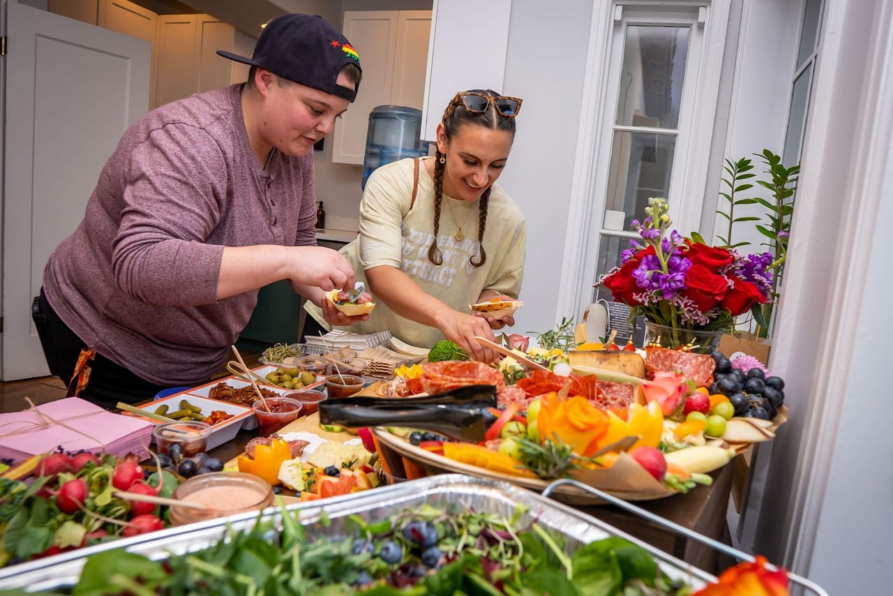 A chef serving from a long table of food and flowers