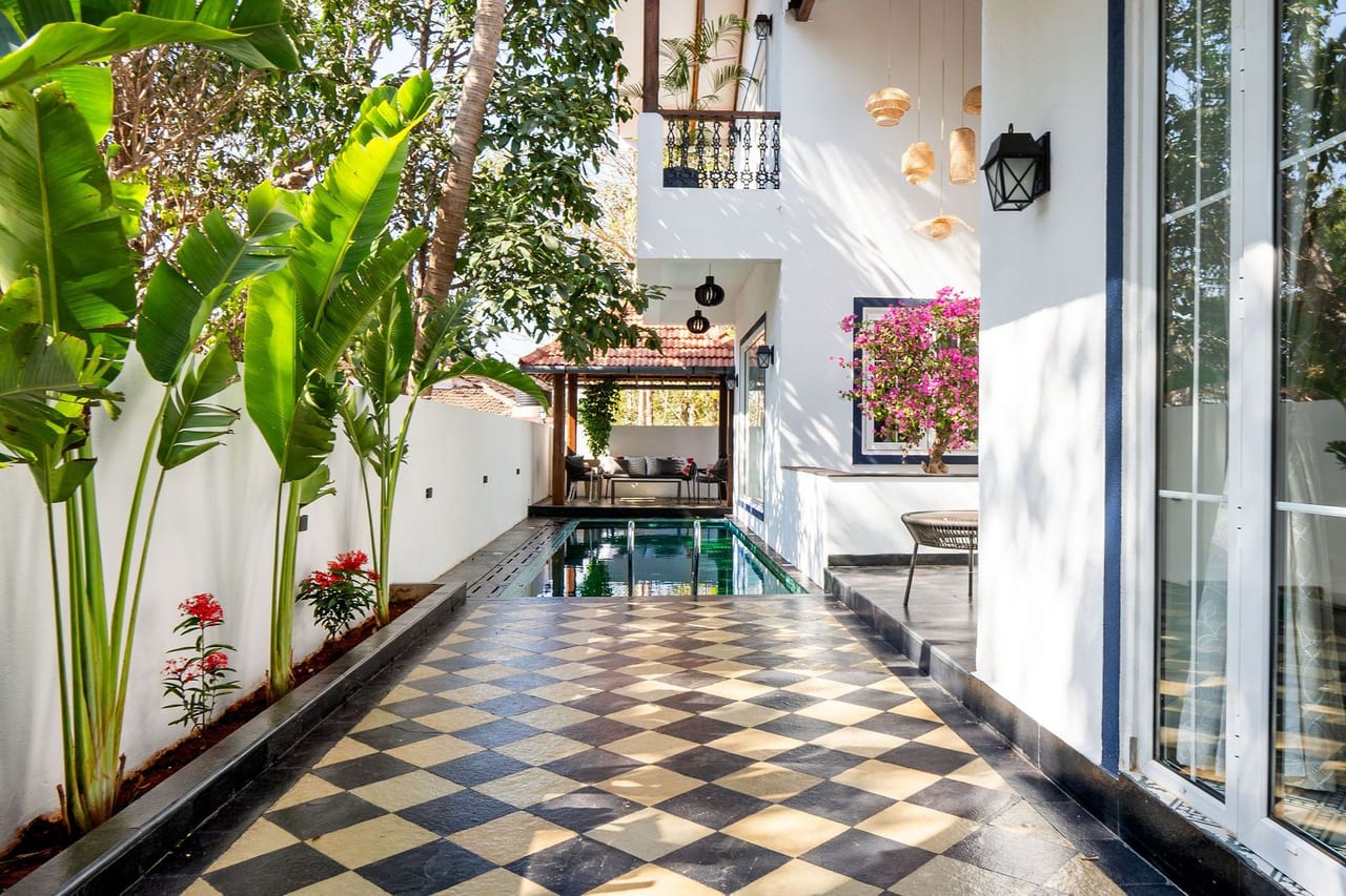 A chequered floor beside a pool under palms, leading to a pavilion