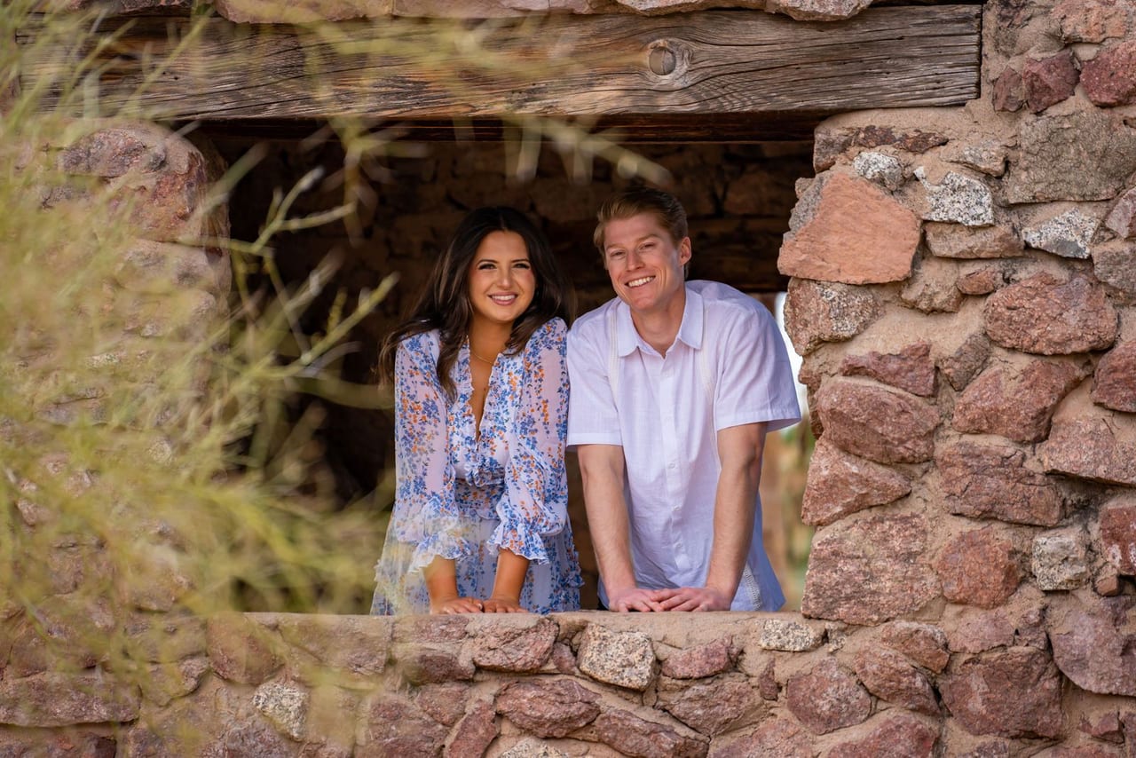 A couple framed in a stone window, smiling at the camera