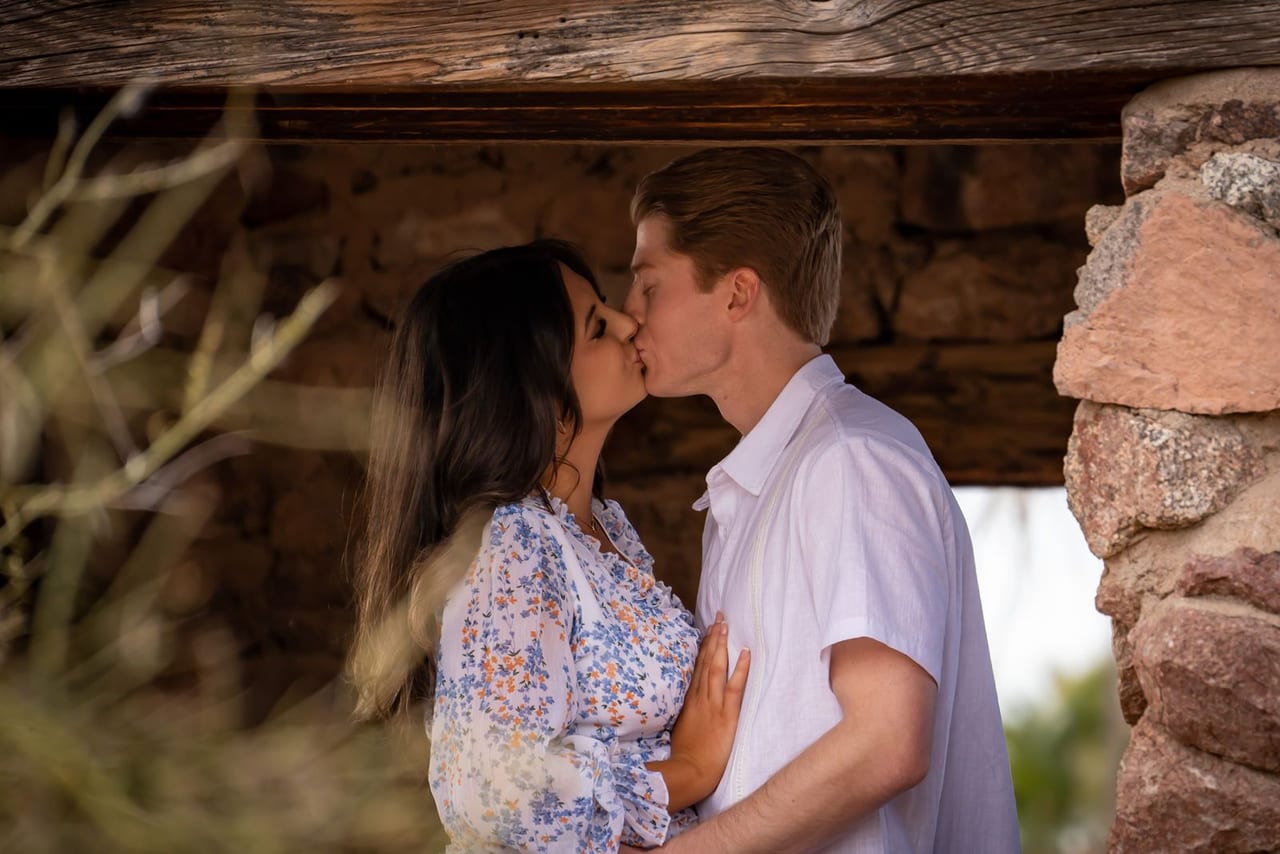 A couple kissing under a stone shelter