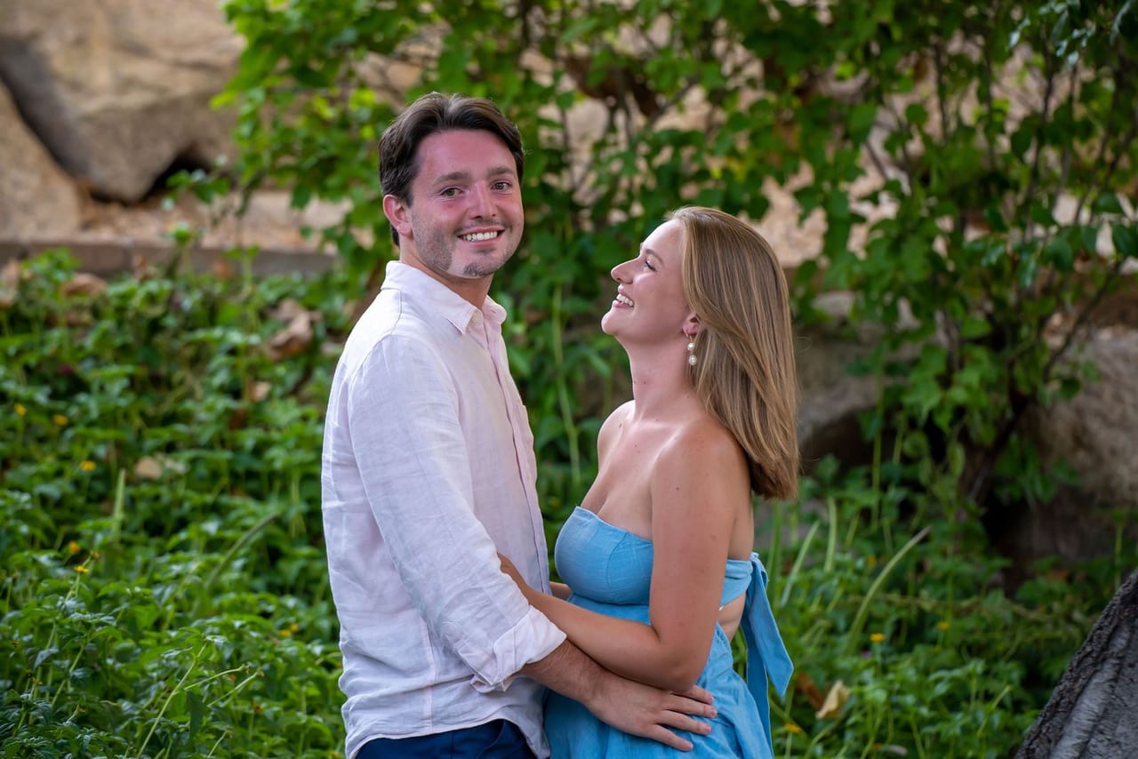 A couple laughing together in a garden of stone walls and greenery