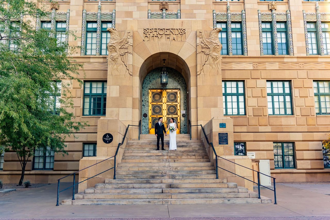 A couple on the steps of a sandstone civic building