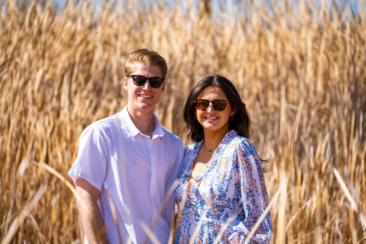 A couple in sunglasses standing in tall golden grass
