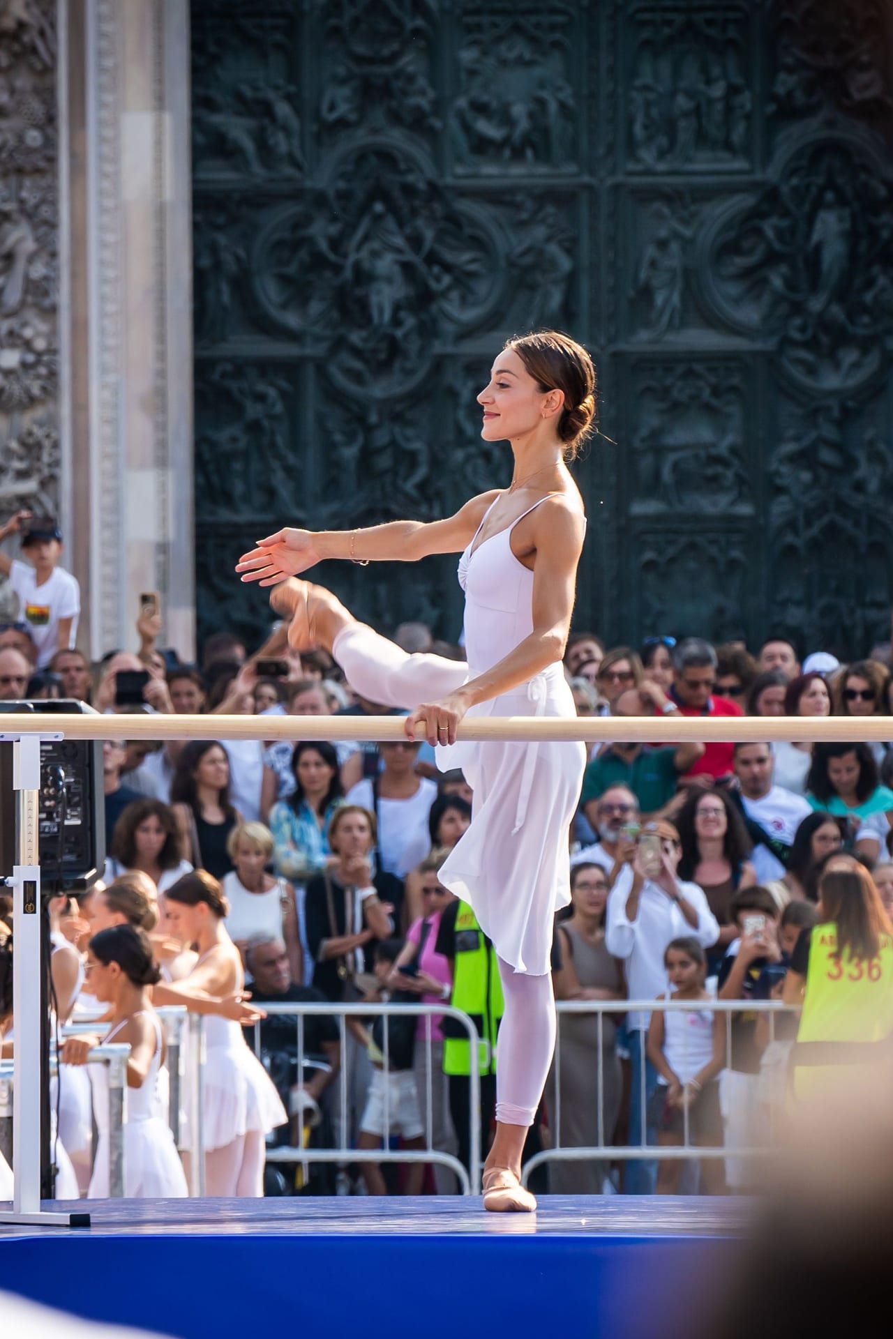 A dancer in white holding a pose on the stage in front of the cathedral doors