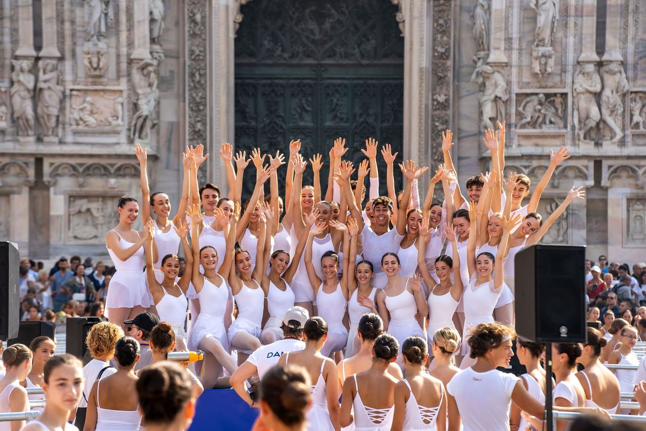 Dancers in white with their arms raised in front of the cathedral façade