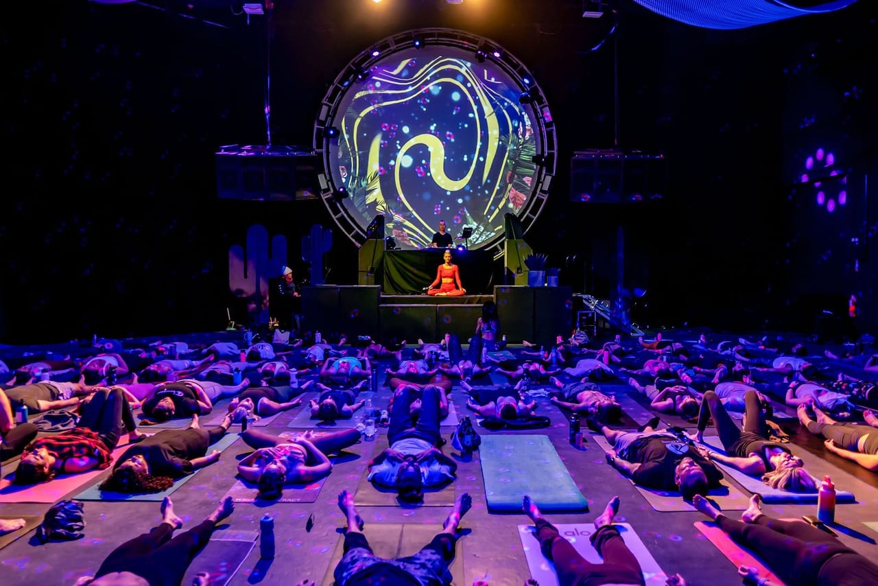 A darkened hall of resting participants facing a glowing circular projection