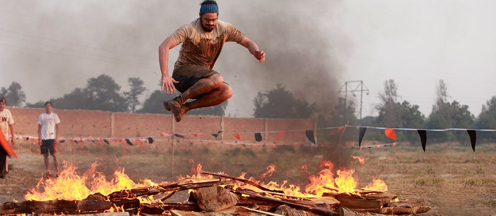 A runner leaping over a line of fire on the Agni obstacle