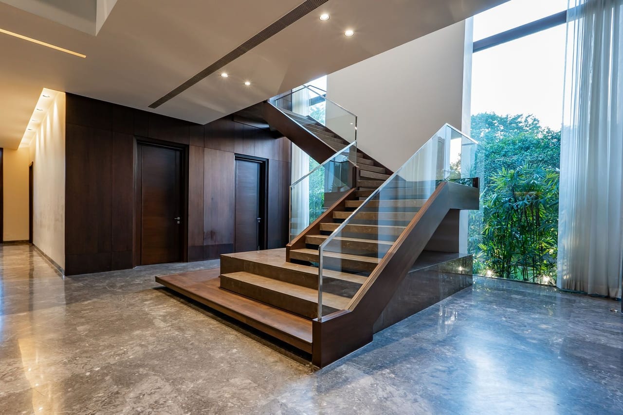 A floating timber staircase beside full-height glass