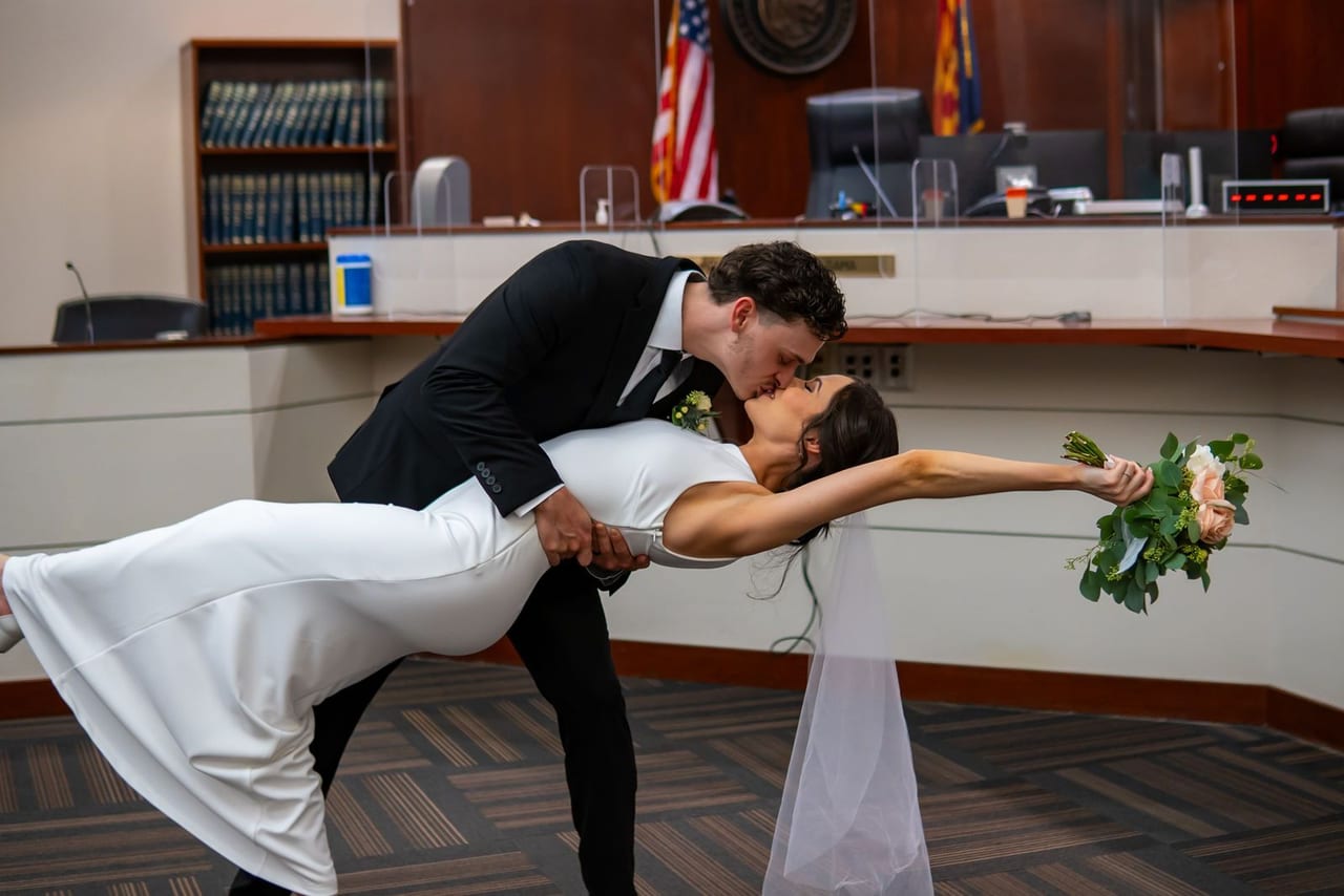 A groom dipping his bride in a courtroom