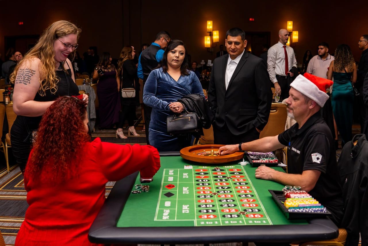 Guests gathered around a roulette table at a casino-themed party