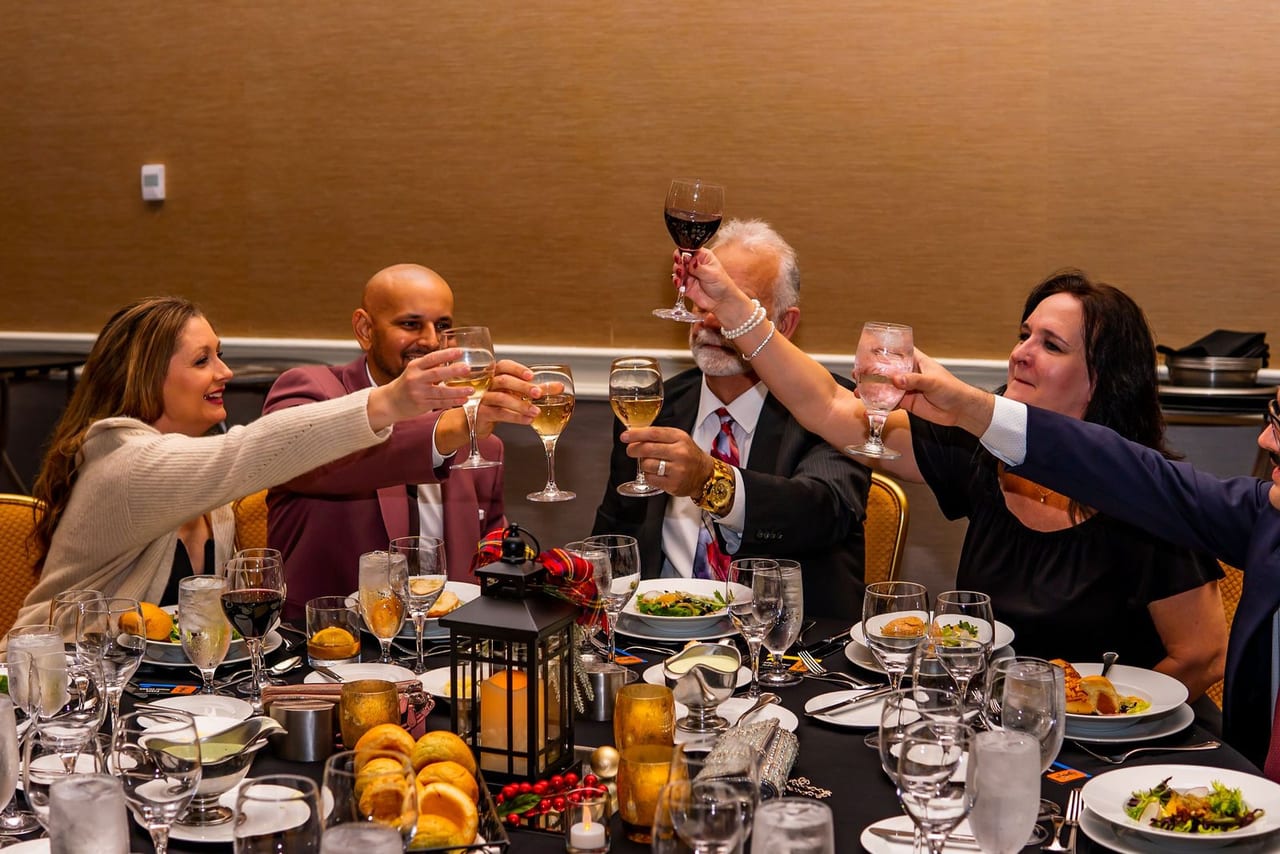 Guests at a round dinner table raising their glasses in a toast