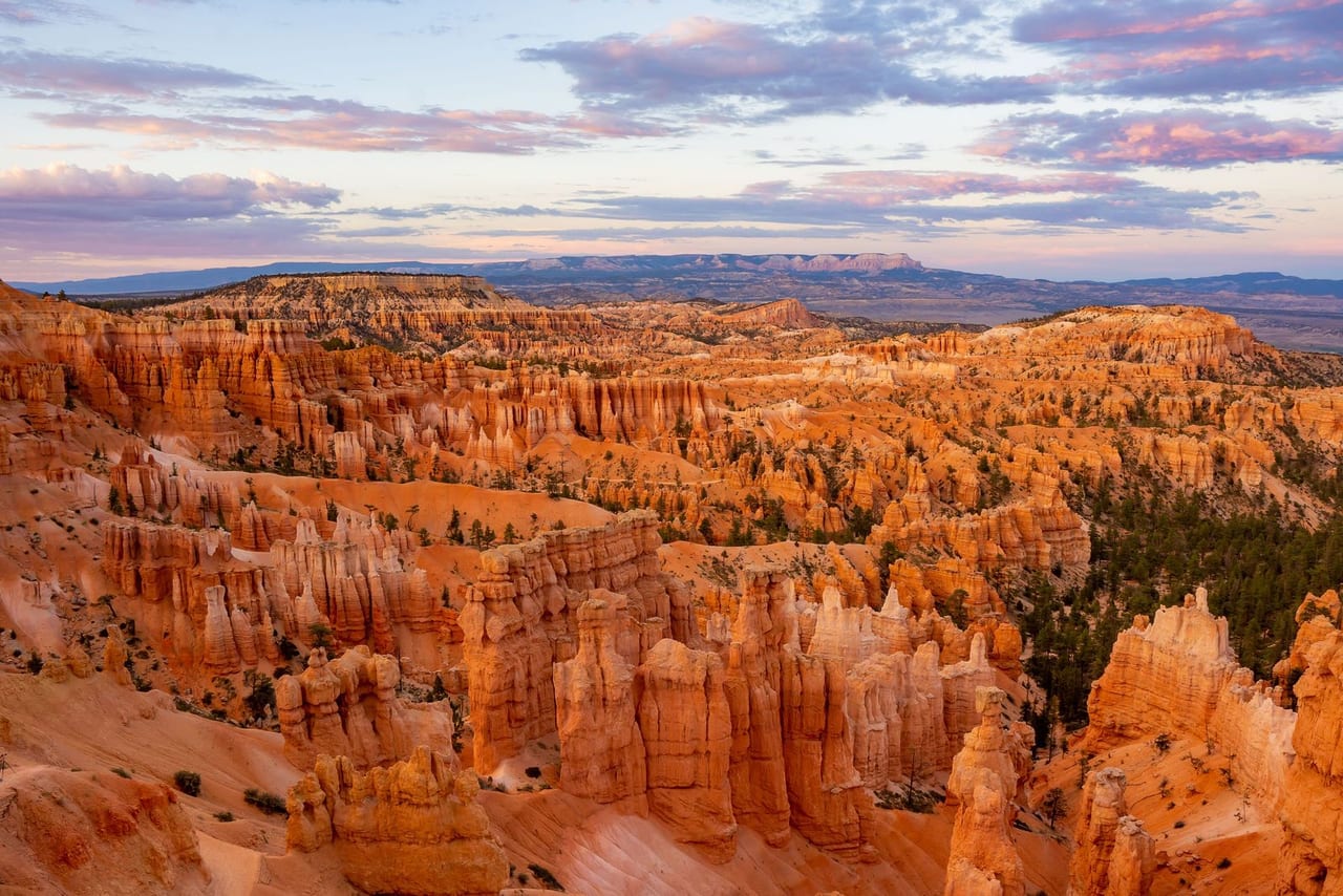 The hoodoo amphitheatre of Bryce Canyon, orange spires under a streaked evening sky