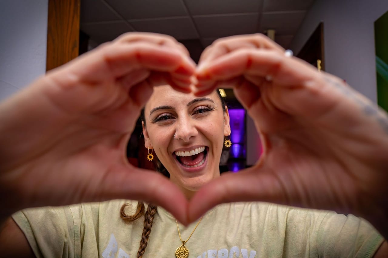 A laughing woman making a heart shape with her hands