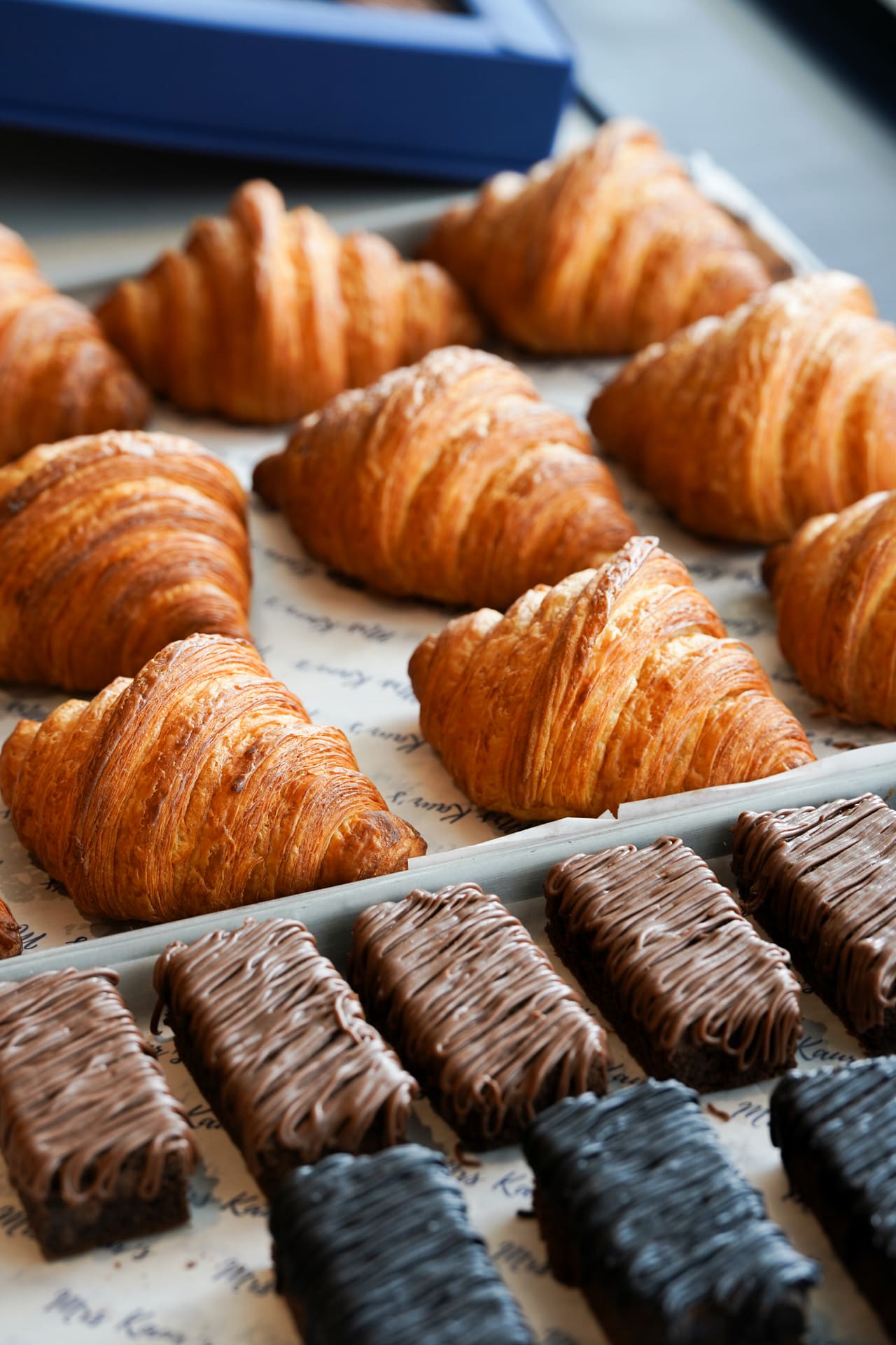 A tray of glossy croissants above a row of chocolate brownies.