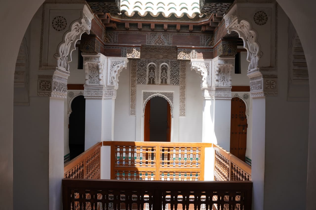 A courtyard of carved white stucco arches above a timber balcony, Morocco.