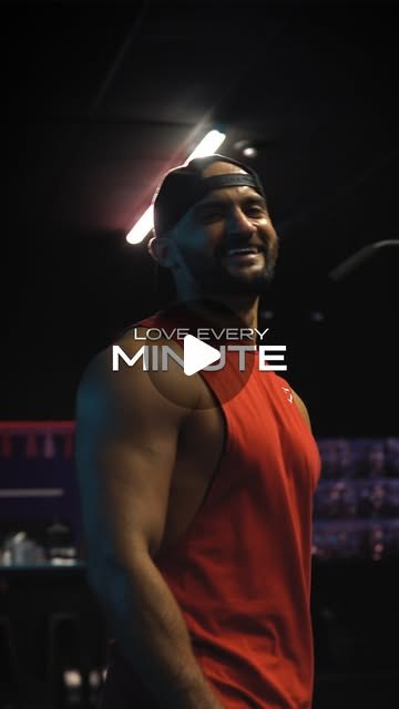 Rish Saini smiling in a red training vest in a dark gym