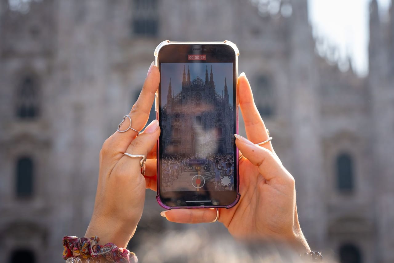 A spectator filming the dancers on a phone held up against the cathedral