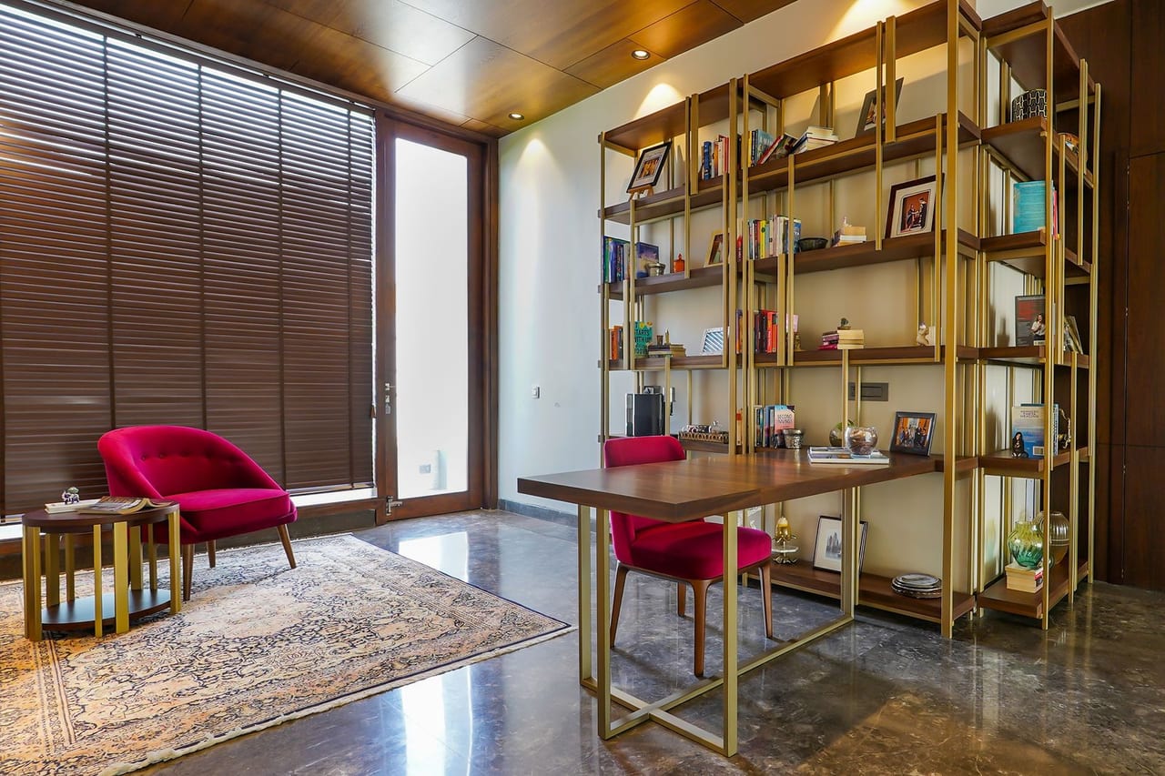 A study with a red armchair and brass shelving