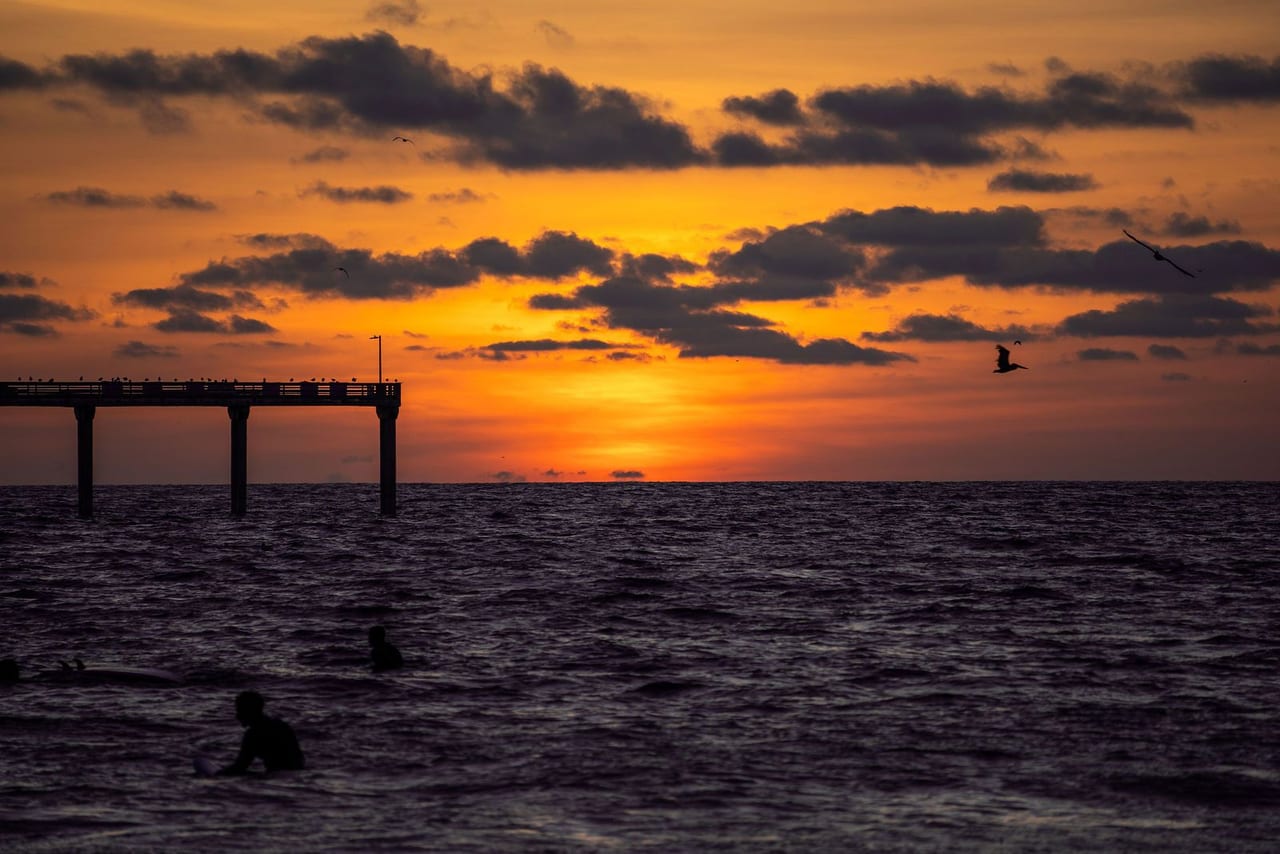 The sun setting over the sea beyond a silhouetted pier