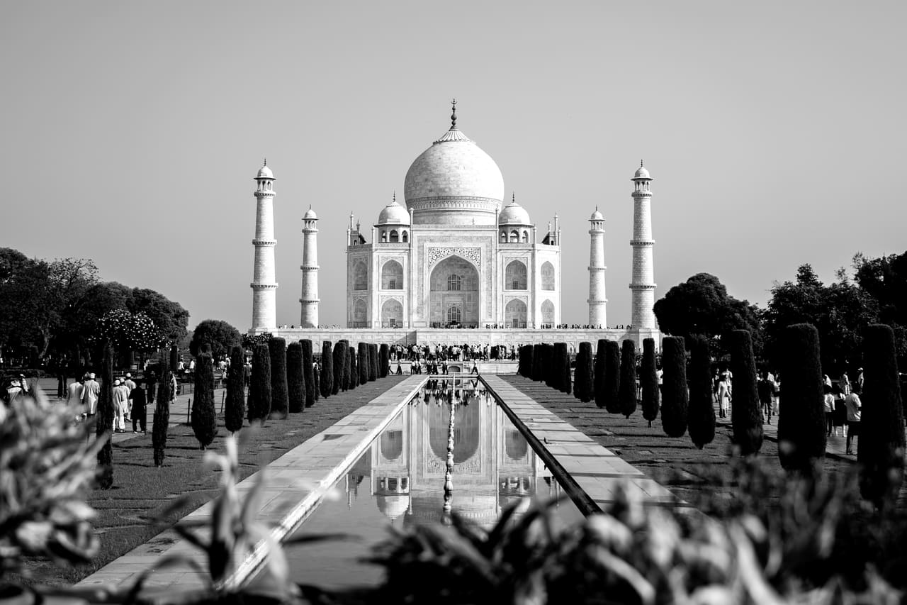 The Taj Mahal in black and white, seen across its marble forecourt.