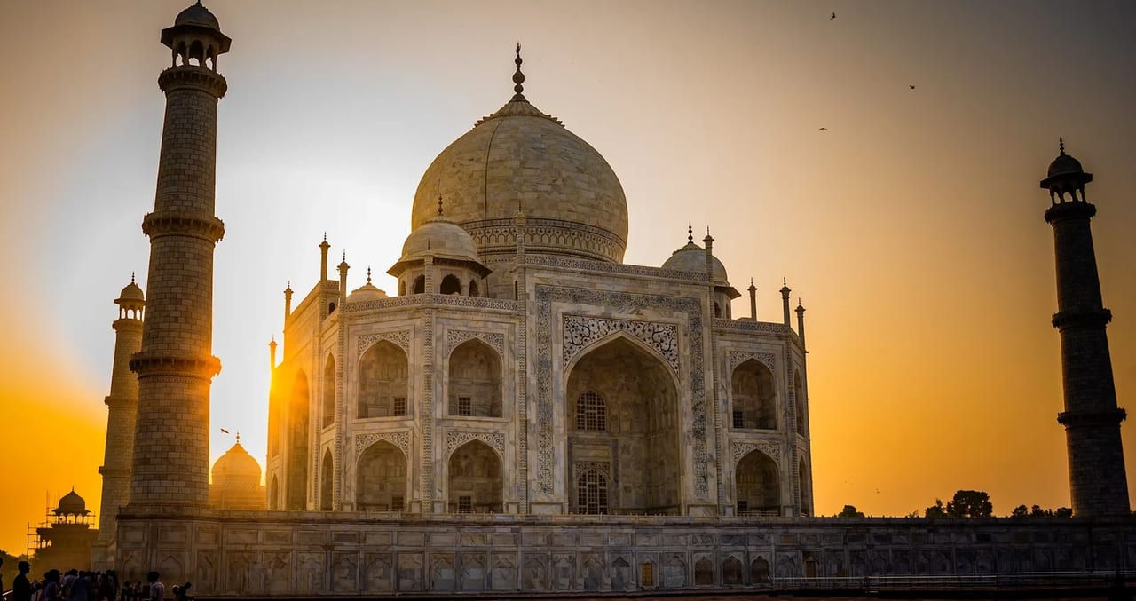 The Taj Mahal and its minarets silhouetted against a golden sky