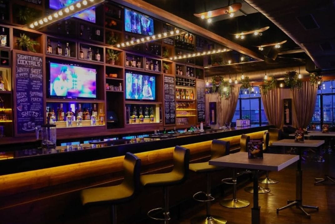 The bar at Underdoggs Jalandhar, lined with screens above the back bar