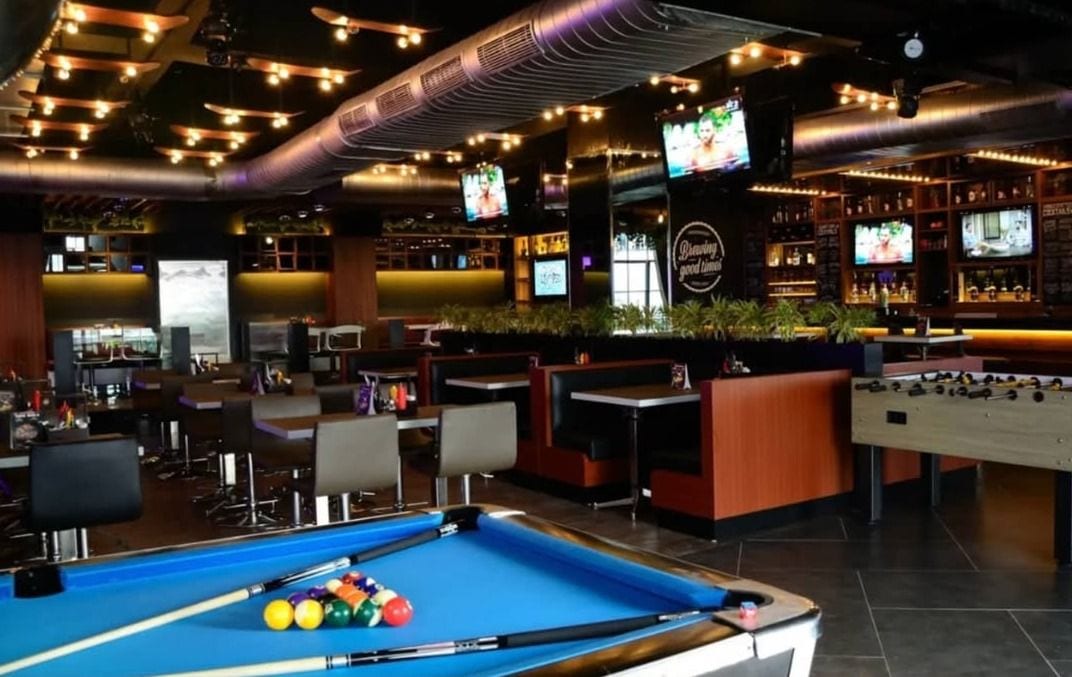 A pool table in front of the bar and booths at Underdoggs Jalandhar