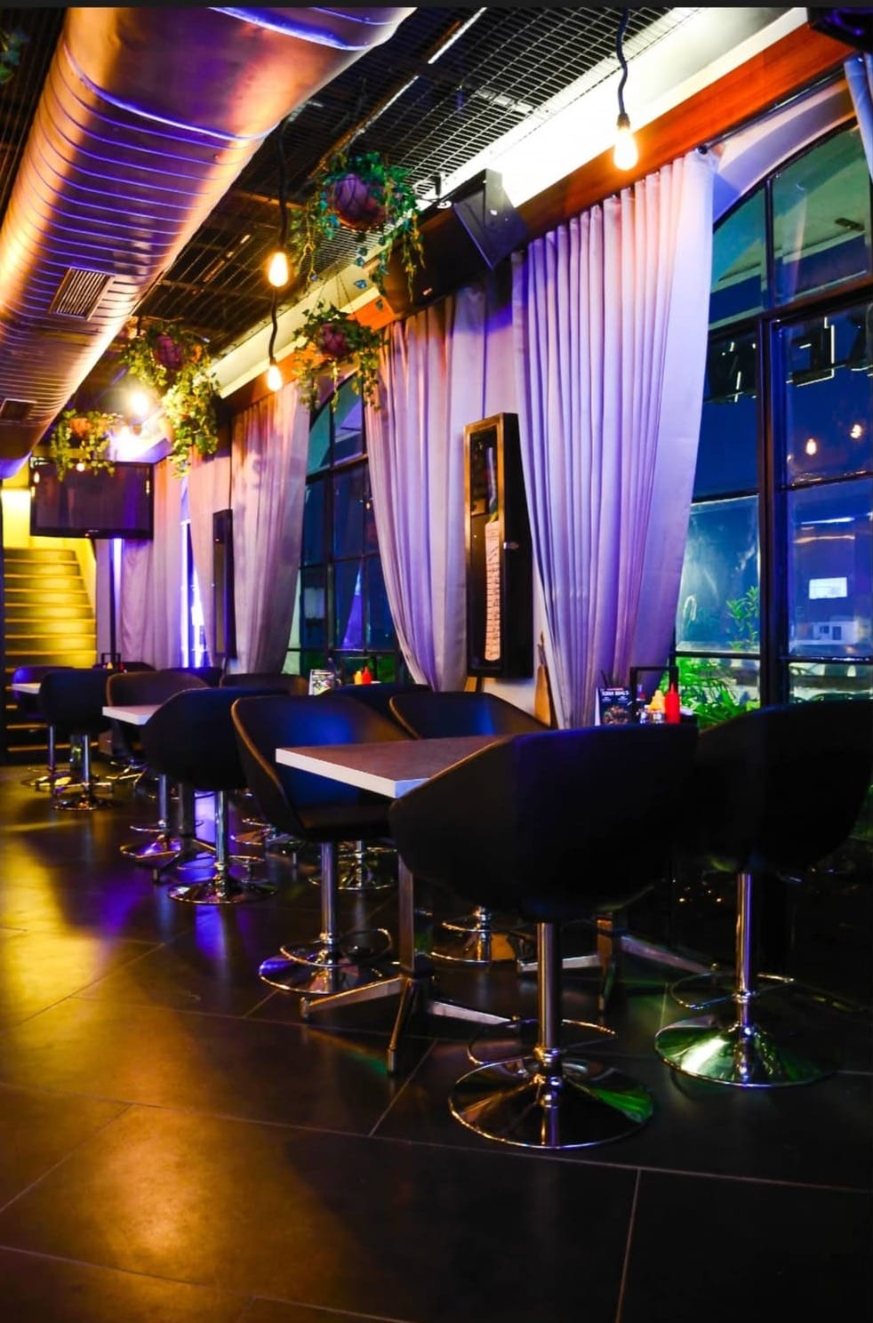 A curtained lounge with high tables beside the windows at Underdoggs Jalandhar