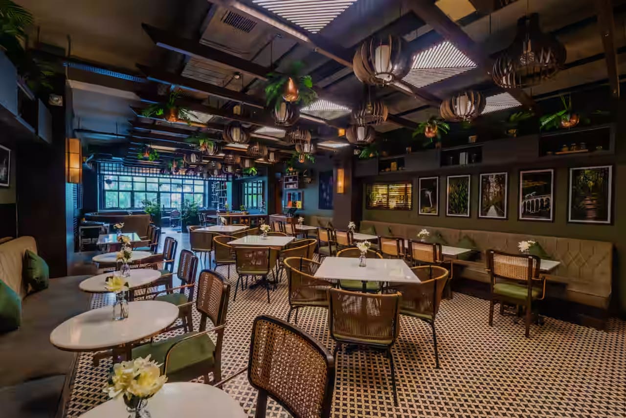 The Uptown Escape dining room: marble-topped tables and cane chairs under strings of hanging lights, with a window wall on the left.