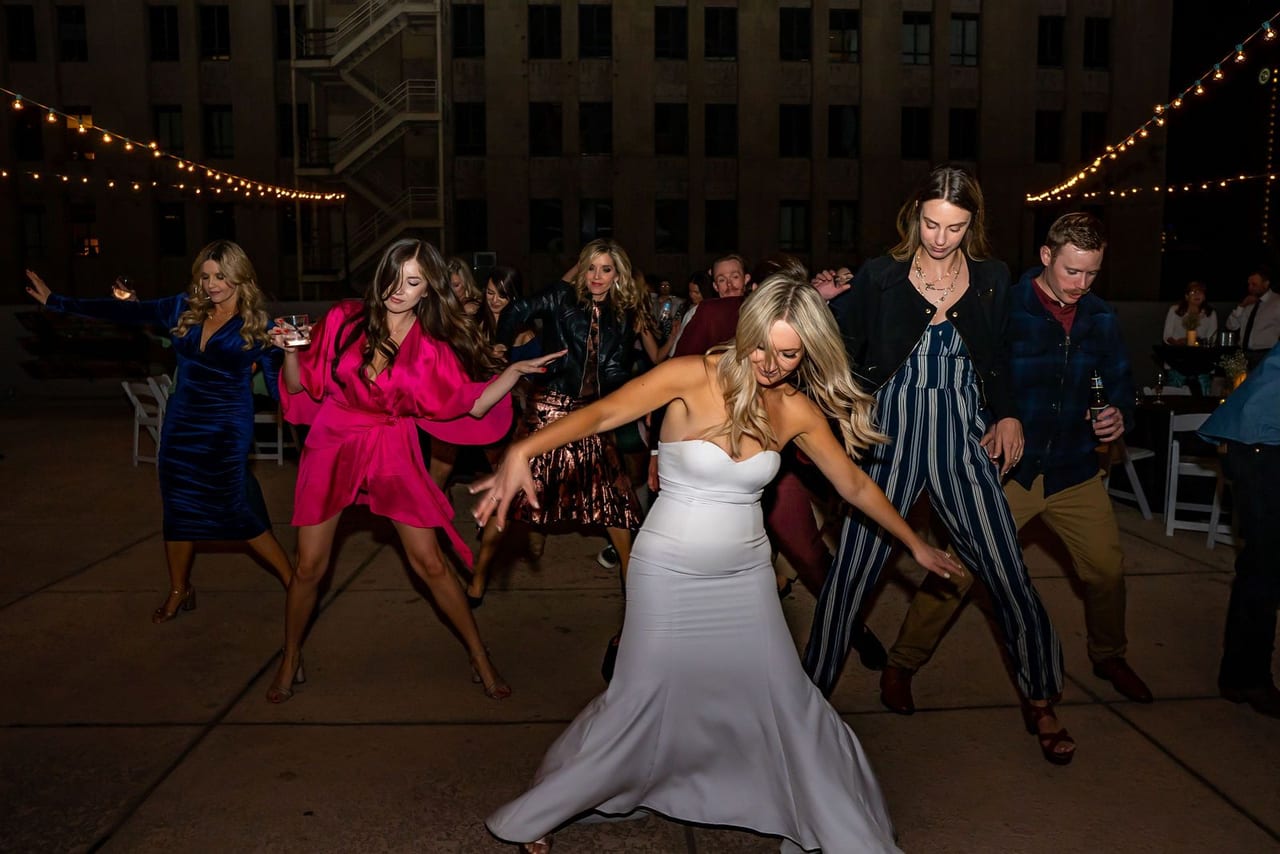Wedding guests dancing on a rooftop at night under string lights