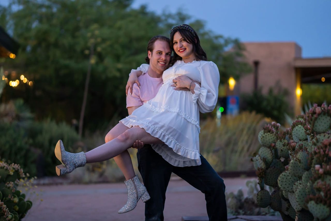 A woman leaping into her partner’s arms on a garden path