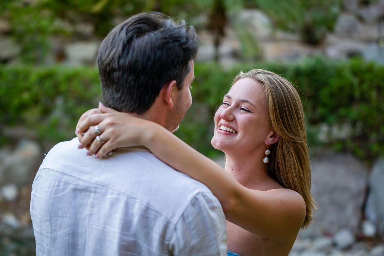 A woman smiling with her arms around her partner’s neck